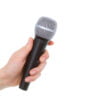 Main féminine tenant un microphone sans fil sur fond blanc
