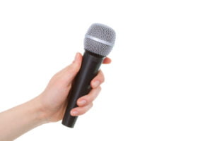 Main féminine tenant un microphone sans fil sur fond blanc
