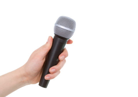 Main féminine tenant un microphone sans fil sur fond blanc