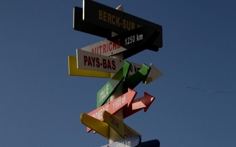 Photo de panneaux signalétiques colorés indiquant plusieurs pays, chacun à plusieurs milliers de km
